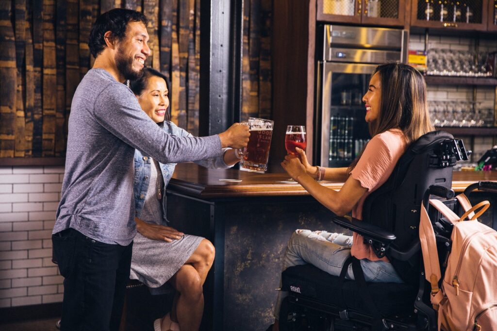 Rollstuhlfahrerin in einer Bar mit Freunden